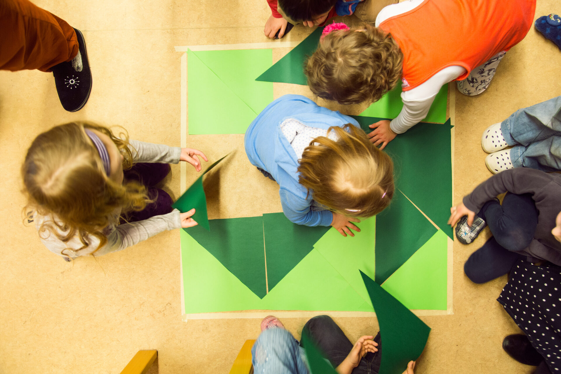 Kinder legen geometrische Formen auf den Fußboden